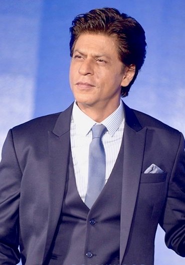 Shah Rukh Khan wearing a three-piece suit with a light shirt and tie