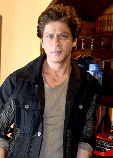 Shah Rukh Khan wearing a dark casual jacket over an olive-grey T-shirt
